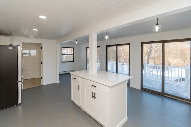 kitchen featuring stainless steel refrigerator, white cabinetry, decorative light fixtures, and a baseboard heating unit