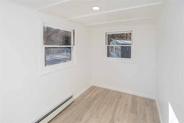 unfurnished room with plenty of natural light, a baseboard radiator, and light wood-type flooring