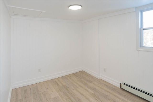 spare room featuring a baseboard heating unit and light hardwood / wood-style flooring