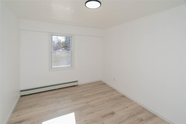 unfurnished room featuring light wood-type flooring and a baseboard heating unit