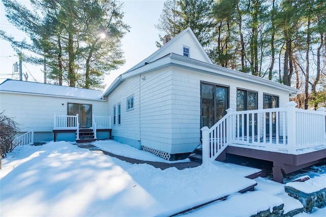 snow covered back of property featuring a wooden deck