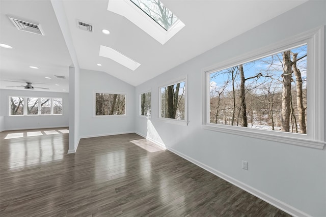 spare room featuring lofted ceiling with skylight, dark wood-type flooring, a wealth of natural light, and ceiling fan