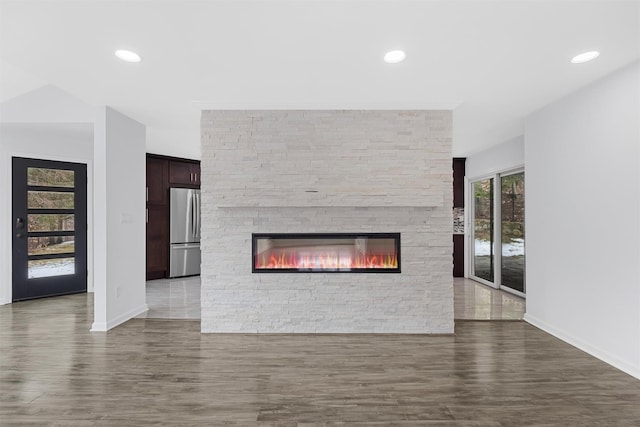 unfurnished living room with dark hardwood / wood-style flooring and a stone fireplace