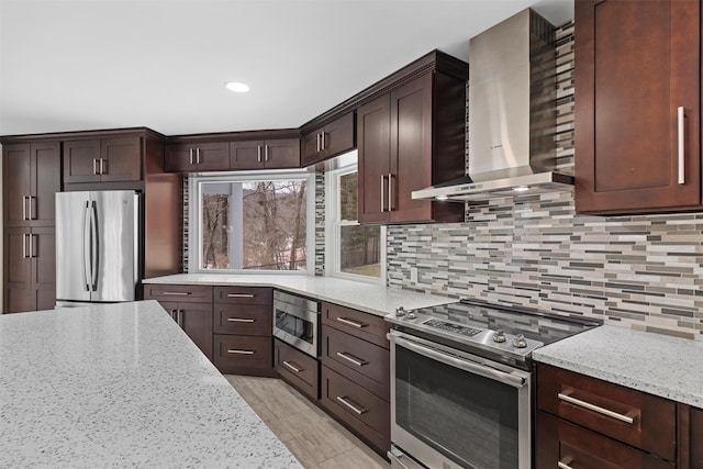 kitchen featuring light stone counters, wall chimney exhaust hood, and appliances with stainless steel finishes