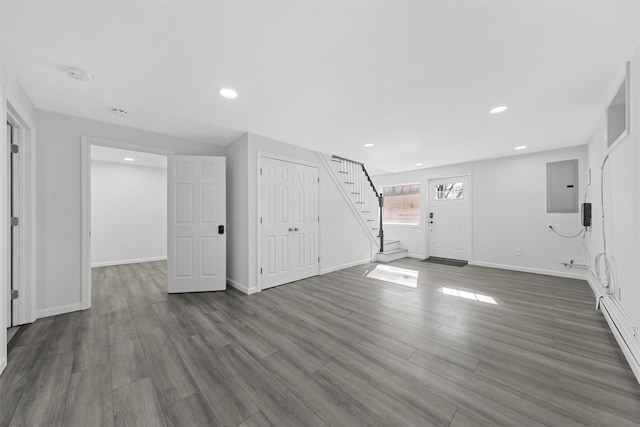 basement featuring dark wood-type flooring, electric panel, and a baseboard heating unit