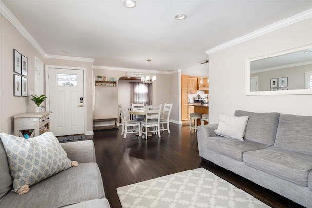 living room with crown molding, a healthy amount of sunlight, dark hardwood / wood-style flooring, and a chandelier