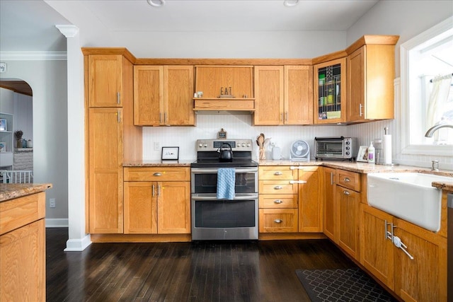 kitchen featuring light stone counters, double oven range, sink, and backsplash