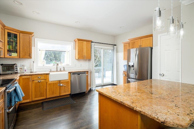 kitchen with sink, decorative light fixtures, dark hardwood / wood-style flooring, stainless steel appliances, and light stone countertops