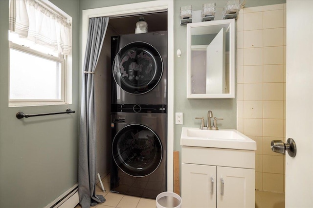 washroom featuring stacked washer / drying machine, sink, baseboard heating, and light tile patterned floors