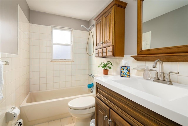 full bathroom featuring tiled shower / bath, vanity, toilet, and tile walls