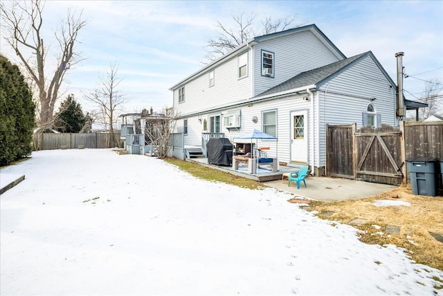 snow covered rear of property with a deck