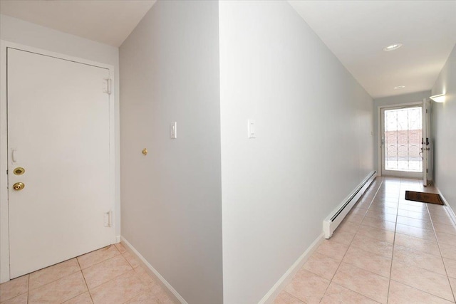 hall with a baseboard heating unit and light tile patterned floors