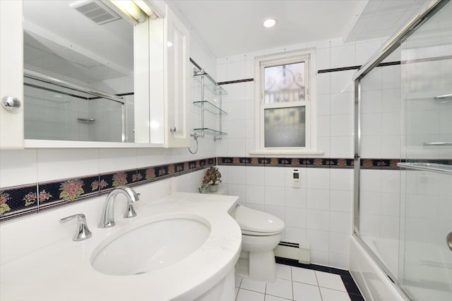 full bathroom featuring sink, tile walls, baseboard heating, toilet, and tile patterned floors