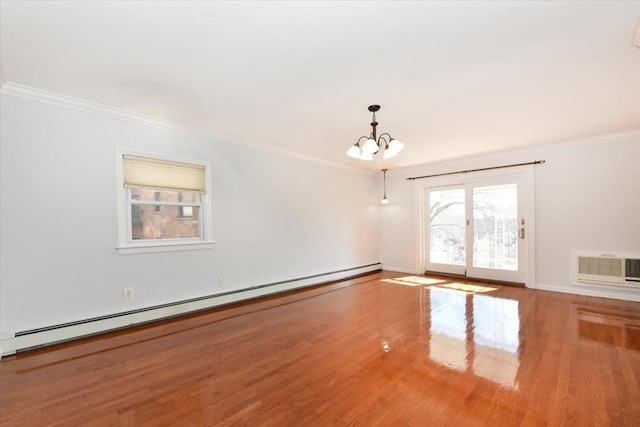 spare room with crown molding, hardwood / wood-style flooring, a wall mounted air conditioner, a baseboard radiator, and a chandelier