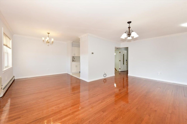 empty room featuring a baseboard heating unit, ornamental molding, a chandelier, and light wood-type flooring