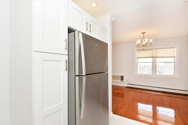 kitchen with crown molding, stainless steel fridge, baseboard heating, white cabinetry, and wood-type flooring