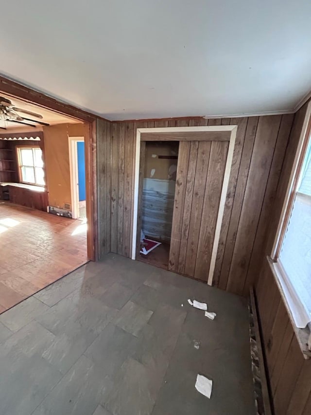 interior space featuring ceiling fan and wood walls