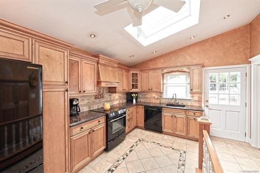 kitchen featuring sink, premium range hood, lofted ceiling with skylight, black appliances, and decorative backsplash