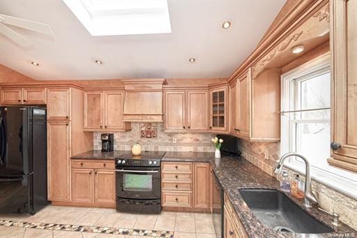 kitchen featuring premium range hood, lofted ceiling with skylight, sink, tasteful backsplash, and black appliances