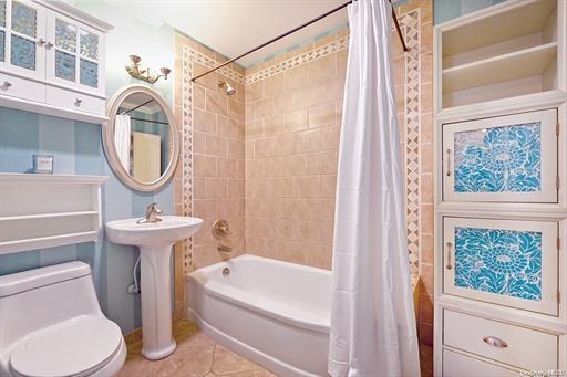 bathroom featuring tile patterned flooring, shower / bath combo, and toilet