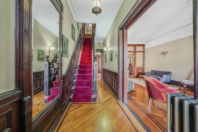 hallway with crown molding, radiator heating unit, and light hardwood / wood-style floors