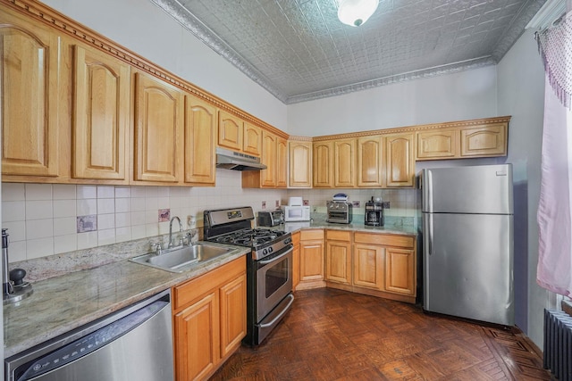 kitchen with sink, tasteful backsplash, appliances with stainless steel finishes, radiator, and dark parquet floors