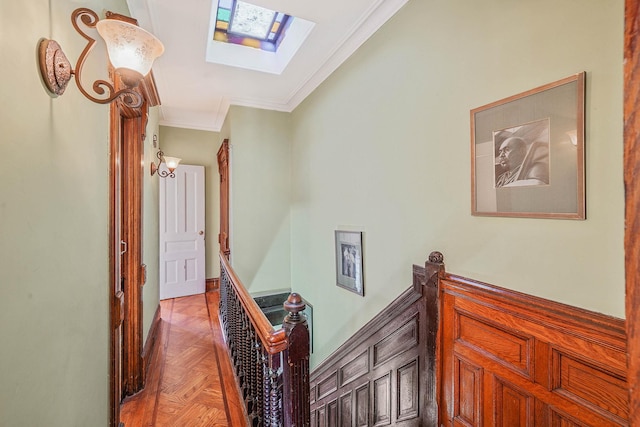 hallway with crown molding, a skylight, and light parquet floors