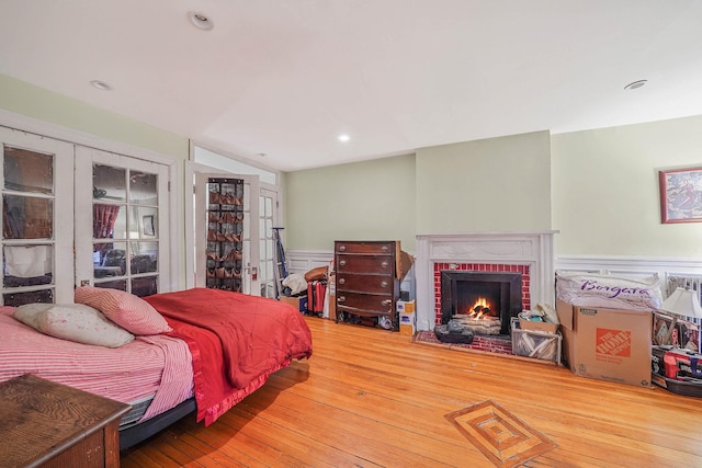 bedroom with hardwood / wood-style flooring and a brick fireplace