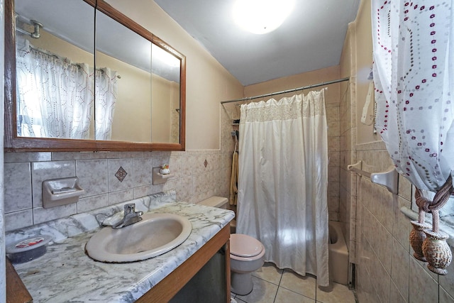 full bathroom with shower / tub combo with curtain, tile patterned floors, toilet, tile walls, and vanity