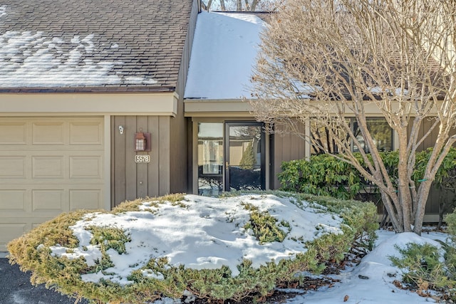 snow covered property entrance featuring a garage