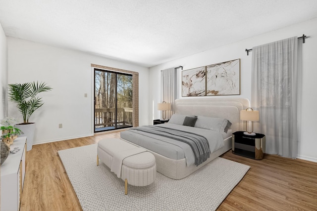 bedroom with a textured ceiling, access to outside, and wood-type flooring