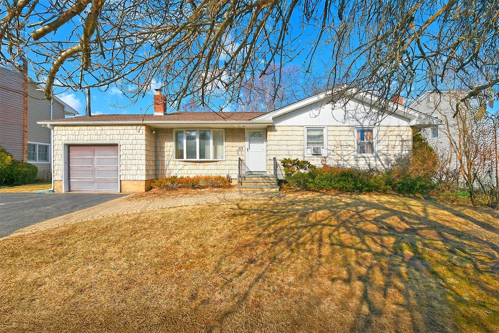 ranch-style home featuring a garage and a front lawn