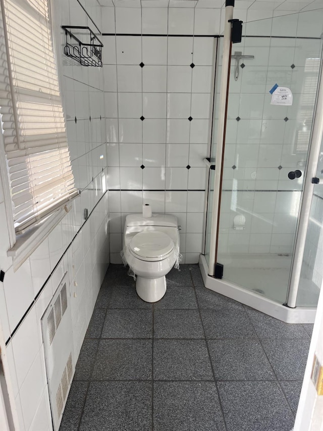 bathroom with tile walls, an enclosed shower, radiator heating unit, and toilet