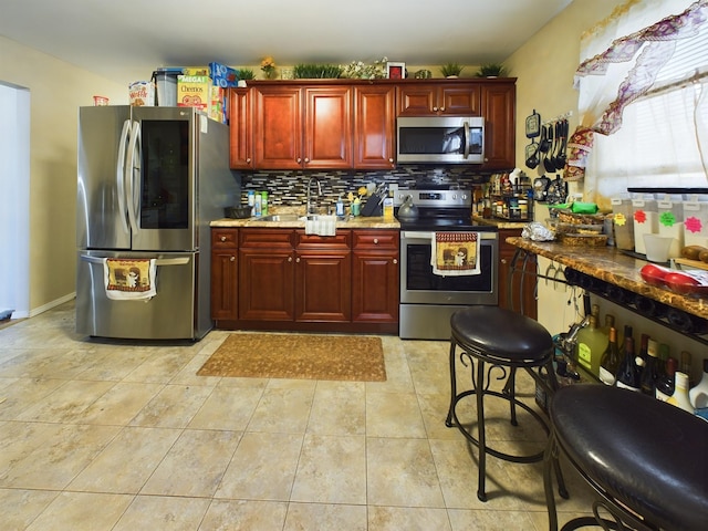 kitchen with light tile patterned flooring, sink, stainless steel appliances, light stone countertops, and decorative backsplash