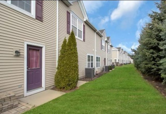 view of side of property featuring a yard and central AC