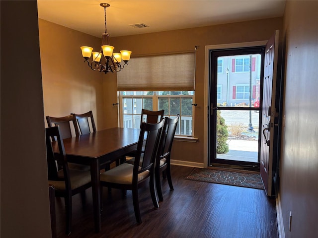 dining area with dark hardwood / wood-style flooring and an inviting chandelier