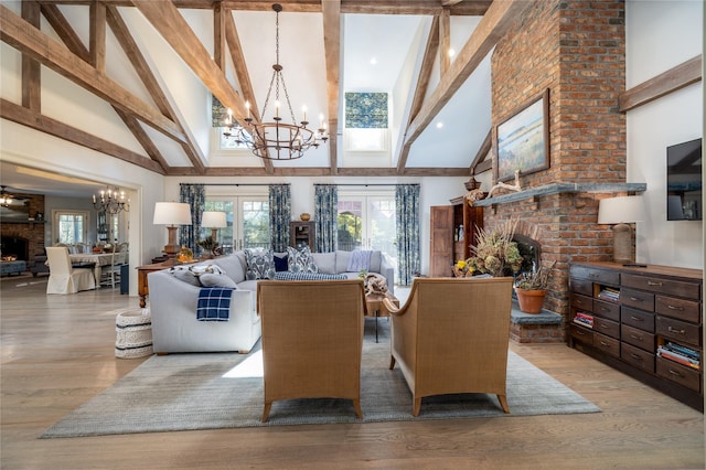 living room featuring light hardwood / wood-style flooring, high vaulted ceiling, a notable chandelier, a fireplace, and beamed ceiling