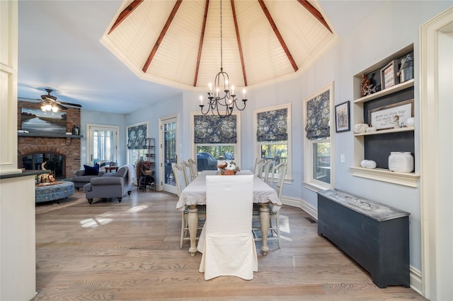 dining area featuring wood ceiling, ceiling fan with notable chandelier, light hardwood / wood-style floors, and a brick fireplace