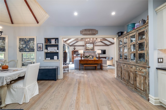 dining room with light hardwood / wood-style flooring, lofted ceiling with beams, and a chandelier