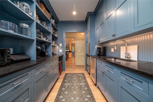 kitchen with ornamental molding, sink, dark stone countertops, and light wood-type flooring