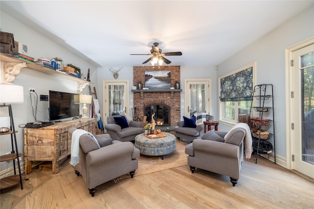 living room with ceiling fan, a fireplace, and light hardwood / wood-style floors