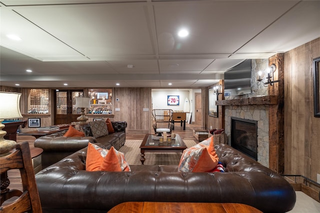 living room featuring a stone fireplace and wooden walls