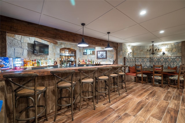 bar featuring hardwood / wood-style flooring, hanging light fixtures, and a drop ceiling