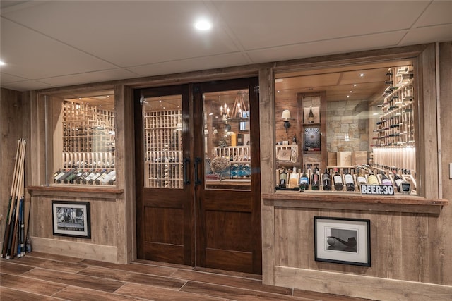 wine room with a drop ceiling, hardwood / wood-style flooring, and wood walls