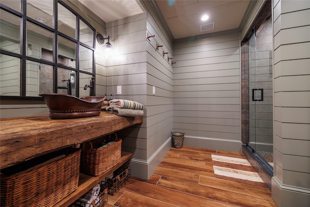 bathroom with a shower with shower door, wood-type flooring, and wood walls