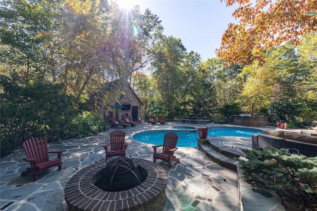 view of swimming pool with an outdoor fire pit, a hot tub, and a patio area