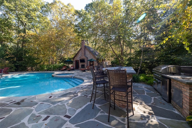 view of swimming pool featuring area for grilling, grilling area, an outdoor brick fireplace, exterior bar, and a patio