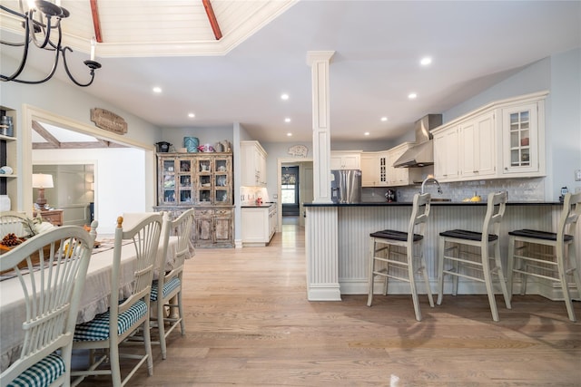 1750 Laurel Lake Dr, Mattituck, NY 11952 - kitchen featuring stainless steel fridge, wall chimney exhaust hood, dark countertops, glass insert cabinets, and decorative backsplash