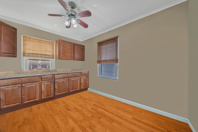 kitchen featuring crown molding, ceiling fan, light stone countertops, and light wood-type flooring