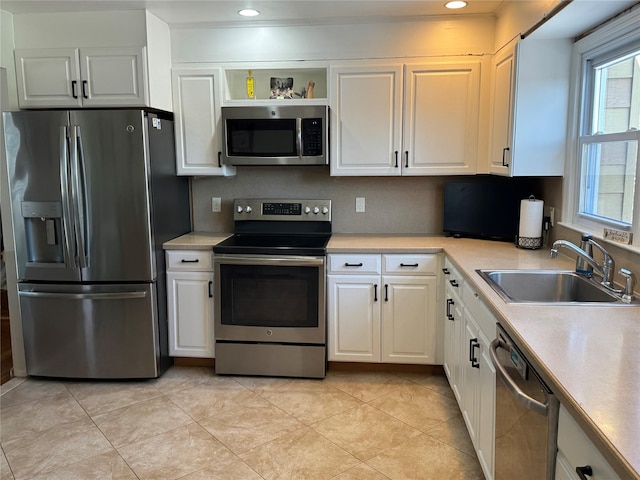 kitchen with white cabinetry, stainless steel appliances, light tile patterned flooring, and sink